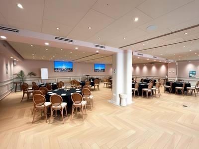 Vue d’ensemble de la salle Paris en tables rondes, écrans au mur