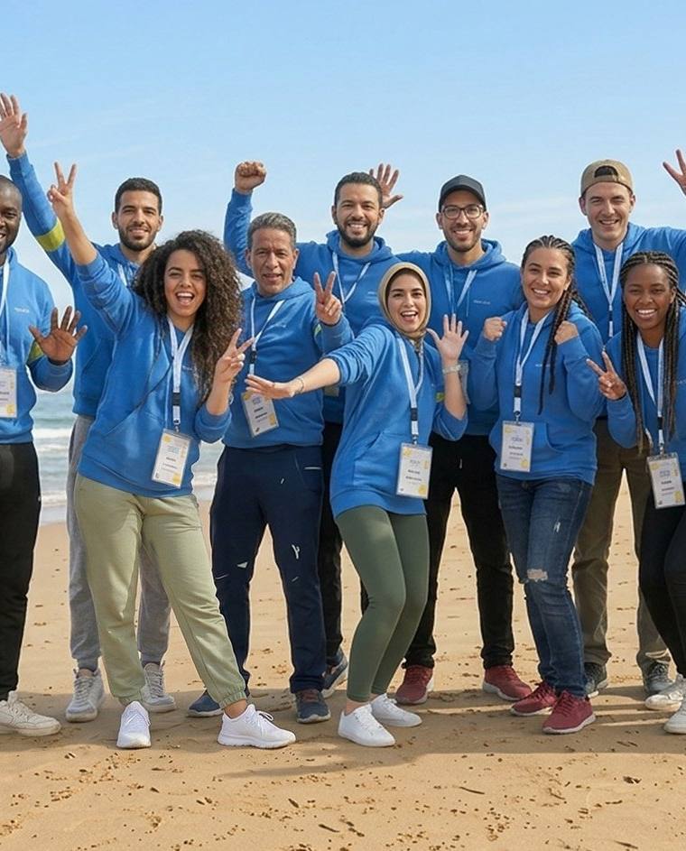 Équipe en tenue bleue célébrant une activité de team building sur la plage